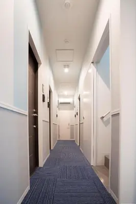 a hallway with white walls and a long corridor at GLOU Higashi Shinjuku in Tokyo