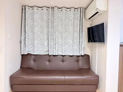 a brown leather couch sitting in front of a curtain at Takadanobaba 3-1F in Tokyo