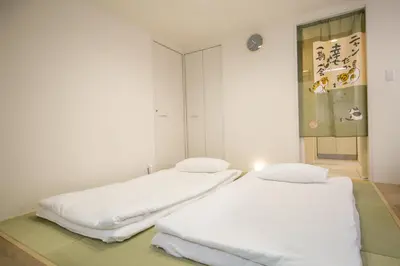 two beds in a room with white walls at Takadanobaba 3-1F in Tokyo