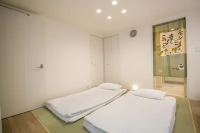 two beds in a room with white walls at Takadanobaba 3-1F in Tokyo