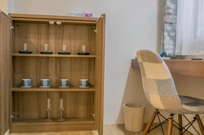 a wooden shelf with glasses and a chair in a room at Takadanobaba 3-1F in Tokyo