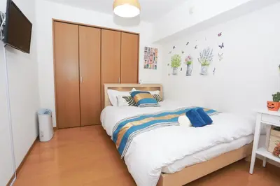 a bedroom with a bed with a large wooden closet at Shinjuku Sunrise Apartment in Tokyo