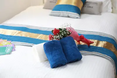two blue towels and a bouquet of flowers on a bed at Shinjuku Sunrise Apartment in Tokyo