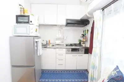 a small kitchen with white cabinets and a refrigerator at Shinjuku Sunrise Apartment in Tokyo
