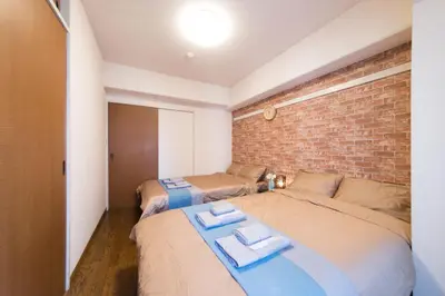 a bedroom with two beds and a brick wall at nestay apartment tokyo akihabara in Tokyo