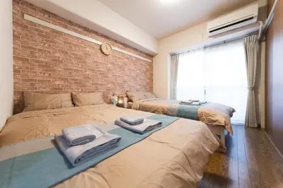 a bedroom with two beds and a brick wall at nestay apartment tokyo akihabara in Tokyo