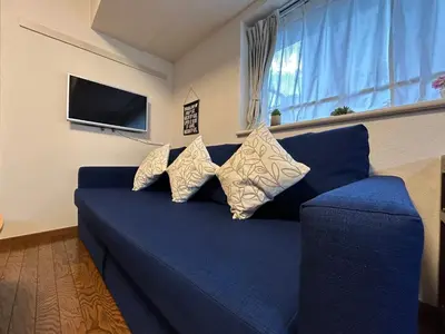 a blue couch with pillows in a living room at nestay apartment tokyo akihabara in Tokyo