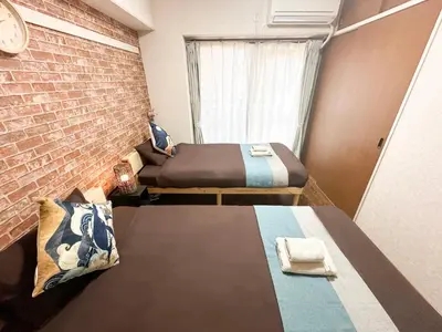 a room with two beds and a brick wall at nestay apartment tokyo akihabara in Tokyo