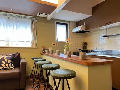 a kitchen with a bar with stools and a couch at nestay apartment tokyo akihabara in Tokyo