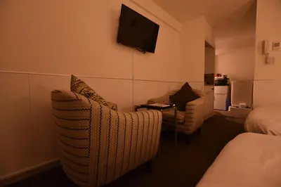 a hotel room with two chairs and a tv on the wall at Residence Condominium KALAHAAI in Tokyo