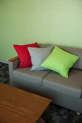 a couch with three different colored pillows on it at Agora Place Tokyo Asakusa in Tokyo