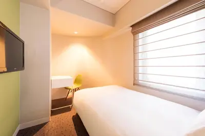 a small bedroom with a bed and a window at Agora Place Tokyo Asakusa in Tokyo