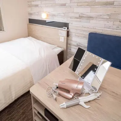 a hotel room with a bed and a desk with a suitcase at Super Hotel Tokyo Hamamatsucho in Tokyo