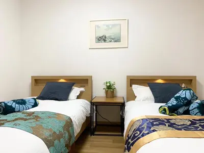 a bedroom with two beds and a table with a picture on the wall at Spring Apartment Shinjuku in Tokyo