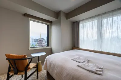 a bedroom with a bed and a chair and a window at Richmond Hotel Asakusa in Tokyo