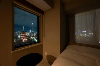 a bedroom with a window with a view of a city at Richmond Hotel Asakusa in Tokyo