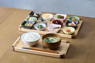 a table topped with three wooden trays with bowls of food at Hamacho Hotel Tokyo in Tokyo