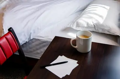 a cup of coffee on a wooden table next to a bed at Hotel Wing International Tokyo Akabane in Tokyo