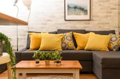 a living room with a gray couch with yellow pillows at Suiren Residential Suite Tokyo in Tokyo