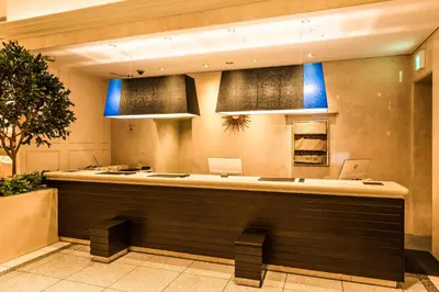 a lobby with a large counter with blue lights at HOTEL MYSTAYS PREMIER Omori in Tokyo