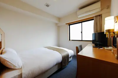 a hotel room with a bed and a desk with a television at Chisun Inn Keikyu Kamata in Tokyo