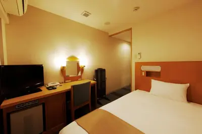 a hotel room with a bed and a desk with a television at Chisun Inn Keikyu Kamata in Tokyo