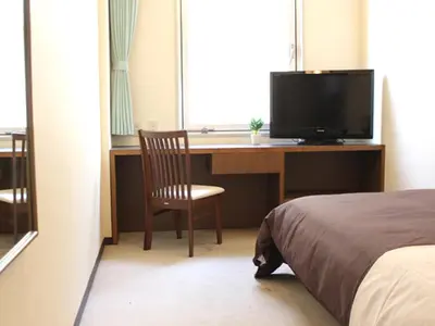 a bedroom with a desk with a television and a bed at HOTEL LiVEMAX BUDGET Tokyo Kiba in Tokyo