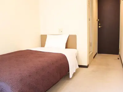 a bedroom with a bed with a brown and white blanket at HOTEL LiVEMAX BUDGET Tokyo Kiba in Tokyo