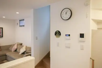 a living room with a couch and a clock on a wall at Uhome Ikebukuro Villa 2 in Tokyo