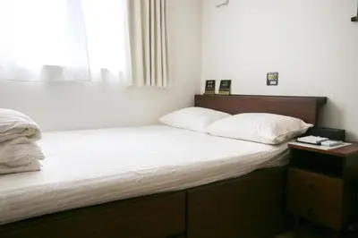 a bedroom with a bed with white sheets and a window at Uhome Ikebukuro Villa 2 in Tokyo