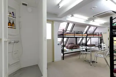 a room with two bunk beds and a table and chairs at Yushima Okachimachi Hotel in Tokyo
