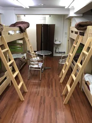 a room with bunk beds and a table and chairs at Yushima Okachimachi Hotel in Tokyo