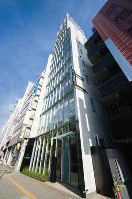 a tall white building with glass windows on a street at Tosei Hotel Cocone Ueno in Tokyo