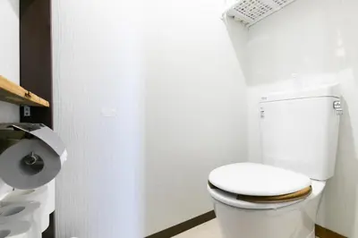 a bathroom with a white toilet and a toilet paper dispenser at TOP EDGE HOSTEL Koenji in Tokyo