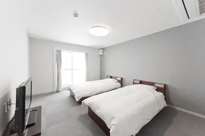 a bedroom with two beds and a television in it at The Shin-Okubo International Hotel in Tokyo