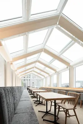 a row of tables and benches in a room with windows at Hotel Comfact in Tokyo
