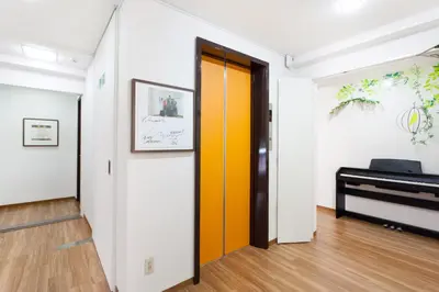 a hallway with a yellow door and a piano at Hanabi Hotel in Tokyo