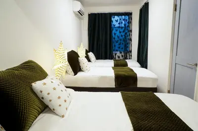a hotel room with three beds and a window at Blue Empire Hotel in Tokyo