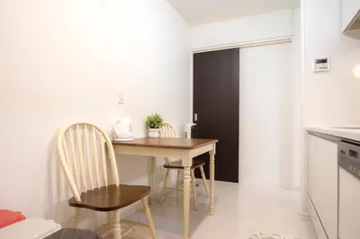 a small kitchen with a wooden table and chairs at COCO Shinjuku HOTEL in Tokyo