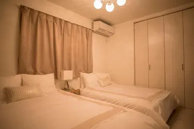 a bedroom with two beds and a cabinet and a lamp at COCO Shinjuku HOTEL in Tokyo