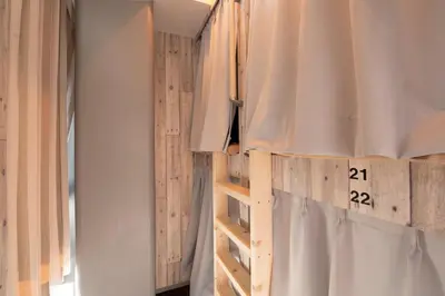 a bedroom with a bed and a ladder with a clock on the wall at bnb+ Kanda Terrace Ogawamachi in Tokyo