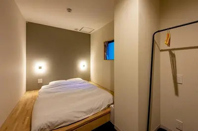 a small bedroom with a bed and a window at plat hostel keikyu minowa forest in Tokyo