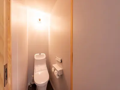 a bathroom with a toilet and a light on the wall at plat hostel keikyu minowa forest in Tokyo