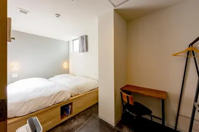 a small bedroom with a bed and a desk at plat hostel keikyu minowa forest in Tokyo