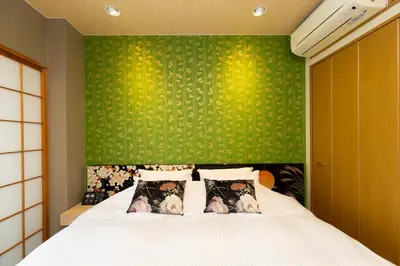 a bedroom with a bed with a green wall at Matsui Building in Tokyo