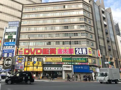 a busy city street with a large building with signs at Matsui Building in Tokyo