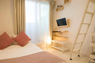 a bedroom with a bed with a ladder and a television at Cozy Vibes Apt Hotel in Tokyo