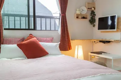 a bedroom with a bed with red and white pillows at Cozy Vibes Apt Hotel in Tokyo