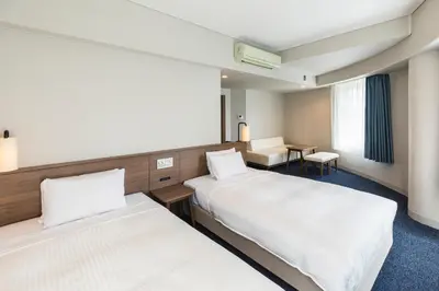a hotel room with two beds and a desk at Sotetsu Fresa Inn Tokyo-Toyocho in Tokyo