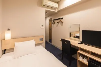 a bedroom with a bed and a desk with a television at Sotetsu Fresa Inn Tokyo-Toyocho in Tokyo